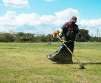 Trabajador desbroza un campo deportivo durante labores de mantenimiento en Ciénega de Flores