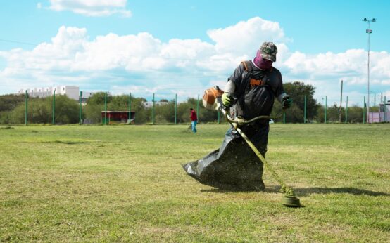Trabajador desbroza un campo deportivo durante labores de mantenimiento en Ciénega de Flores