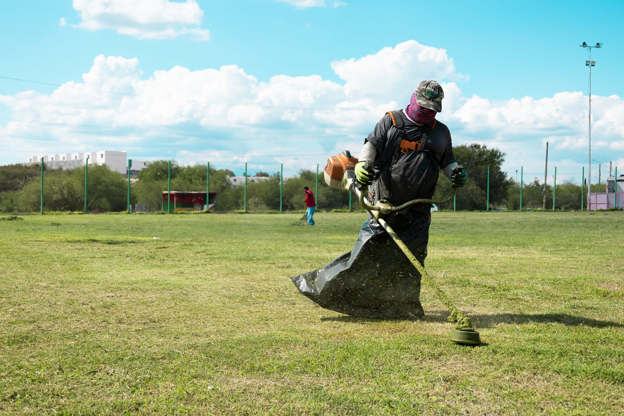 Trabajador desbroza un campo deportivo durante labores de mantenimiento en Ciénega de Flores