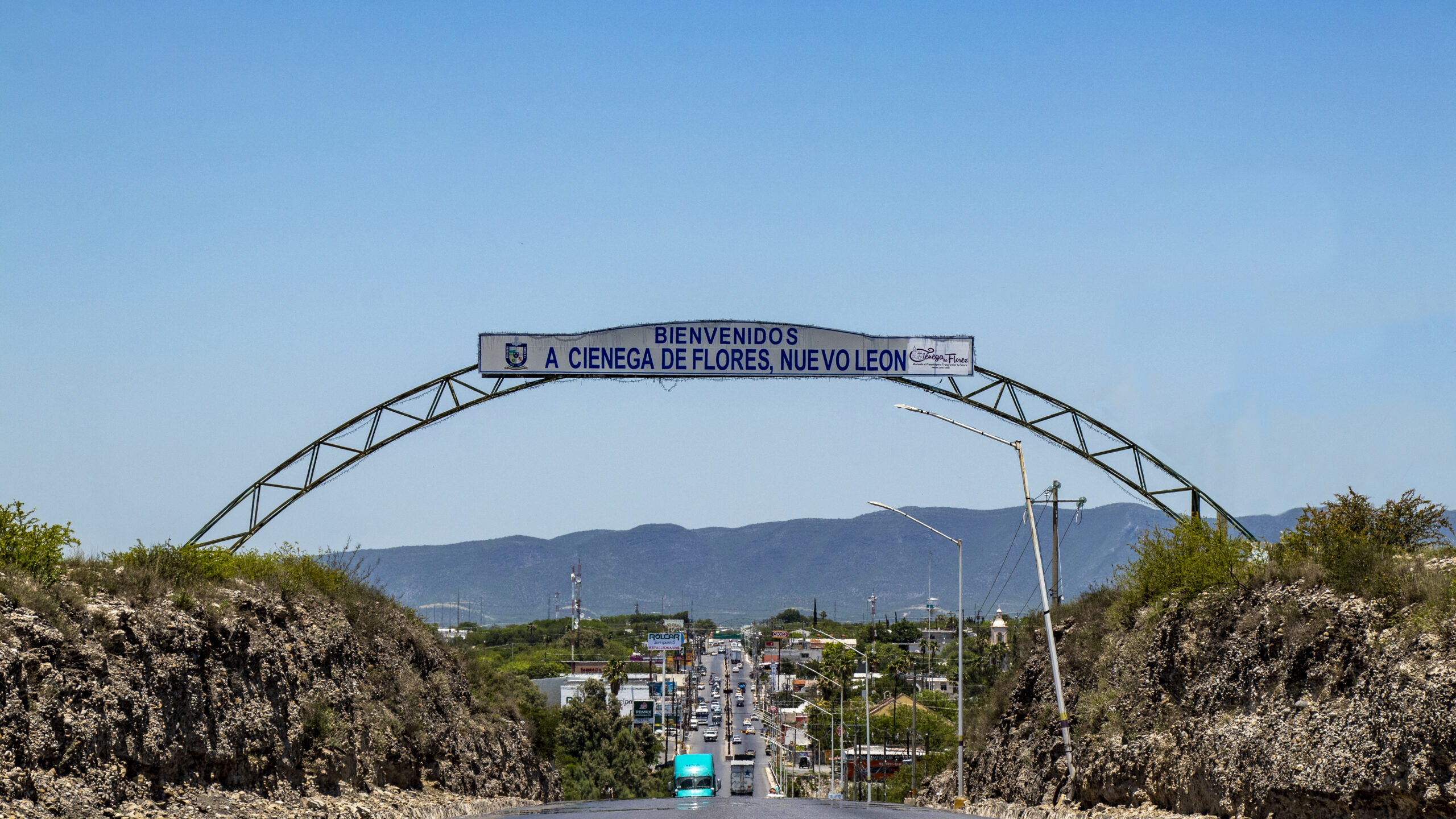 Arco de bienvenida a Ciénega de Flores sobre la carretera, con tráfico vehicular