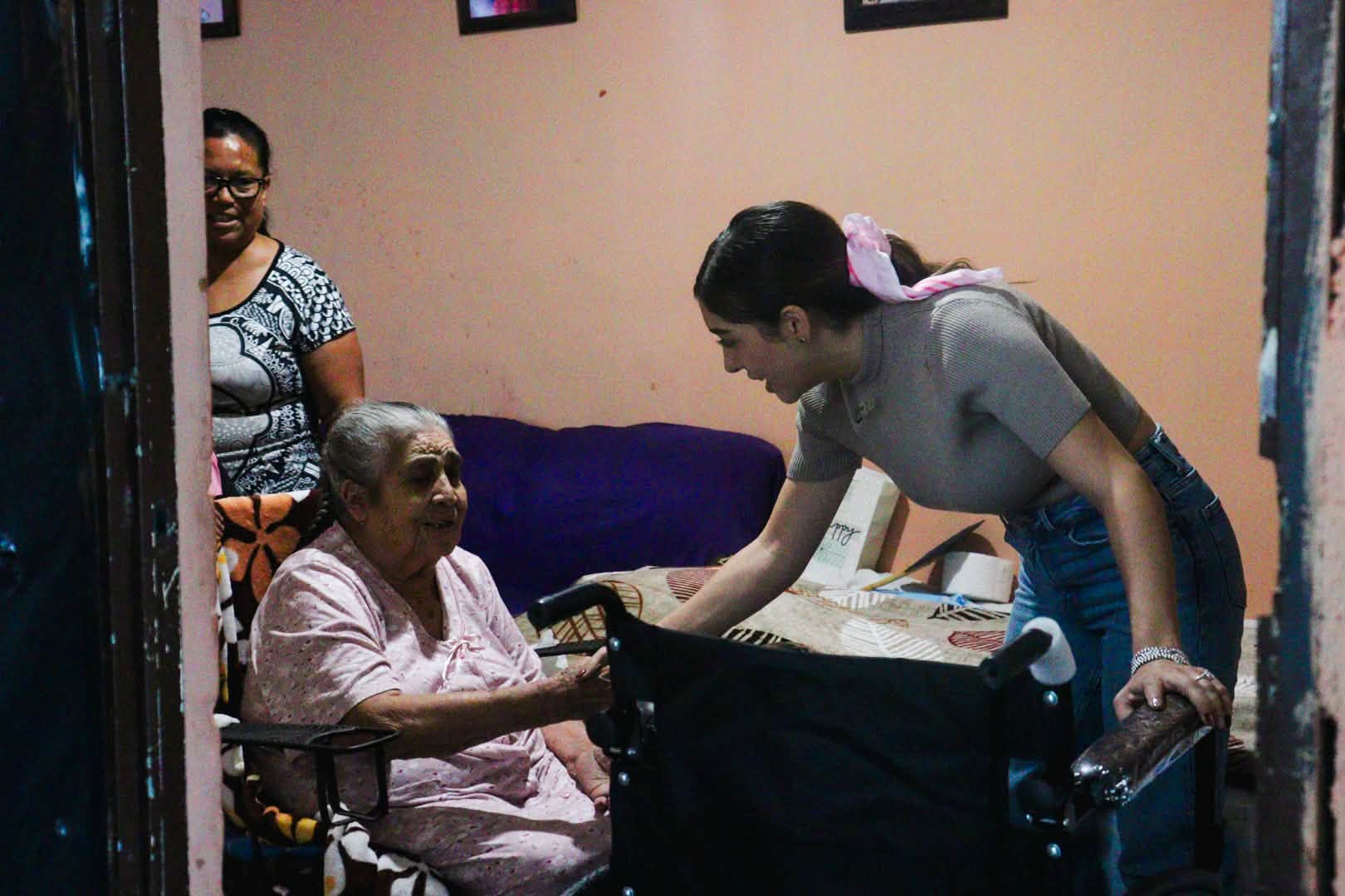 Perla Cavazos conversa con una adulta mayor en una vivienda de Ciénega de Flores