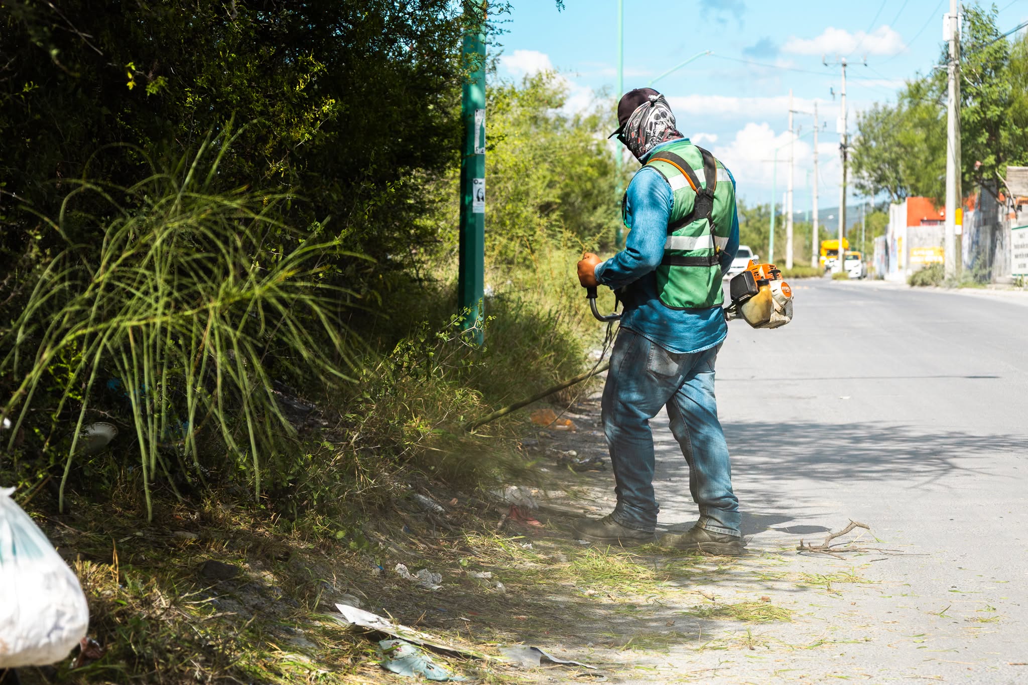 Trabajador realiza labores de deshierbe en el perímetro de un espacio deportivo de Ciénega de Flores