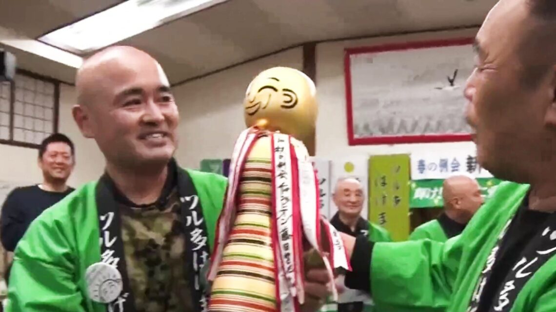 Dos hombres sonrientes con chaquetas verdes durante una celebración del club de Tsuruta