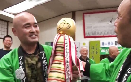 Dos hombres sonrientes con chaquetas verdes durante una celebración del club de Tsuruta