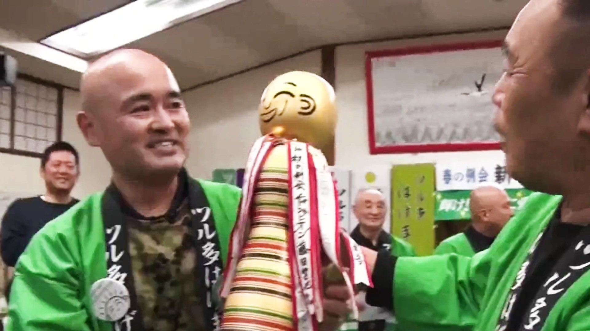 Dos hombres sonrientes con chaquetas verdes durante una celebración del club de Tsuruta
