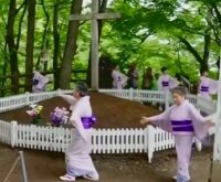 Personas con vestimenta ceremonial frente a un recinto con cruces en Shingo