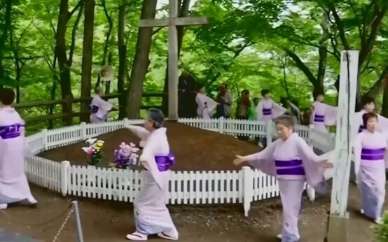 Personas con vestimenta ceremonial frente a un recinto con cruces en Shingo